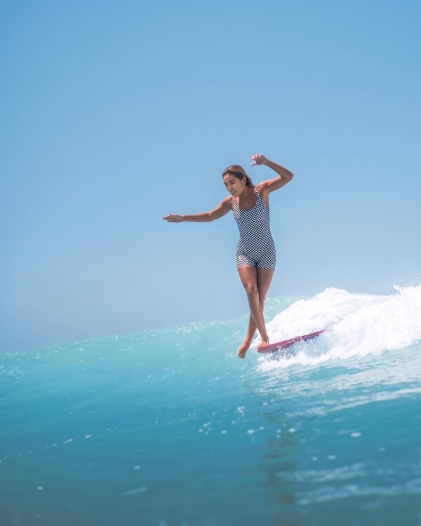 Sirena Yin Yang bodysuit, checkerboard side, surfing on a longboard